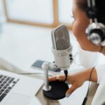 Professional woman recording a podcast or broadcast using a microphone and laptop at a desk.